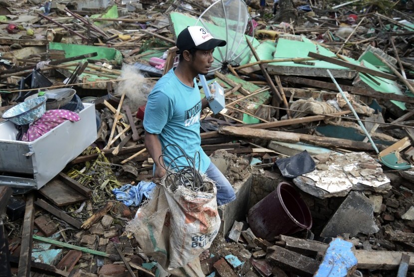 Warga melintasi reruntuhan rumah yang rusak akibat tsunami di Desa Kunjir, Kecamatan Rajabasa, Lampung Selatan, Lampung, Jumat (28/12/2018).