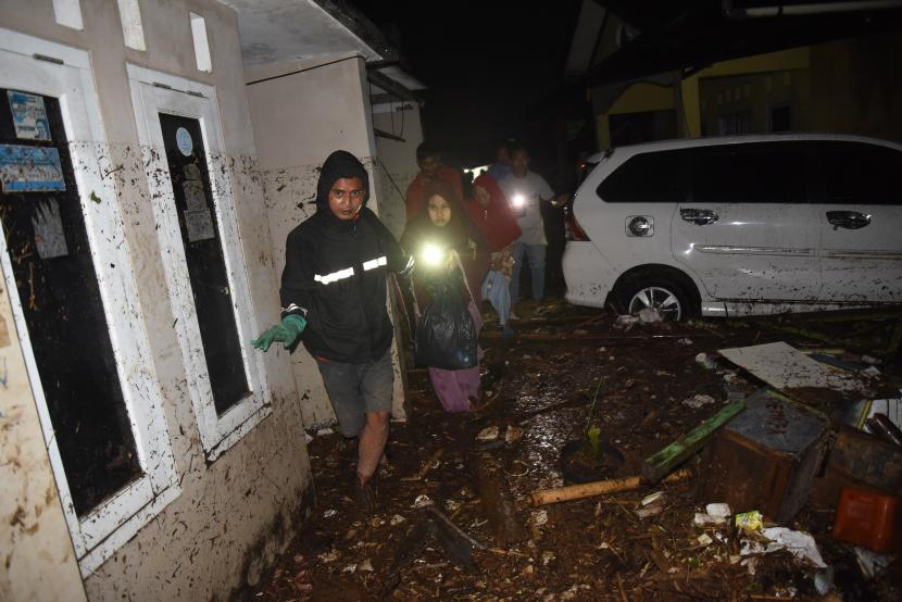 Warga melintasi rumah yang terkena banjir bandang di Desa Mekarsari, Kecamatan Cicurug, Kabupaten Sukabumi, Jawa Barat, Senin (21/9/2020). Pada pukul 20.30, Pusat Pengendali Operasi (Pusdalops) BNPB mencatat sebanyak 12 rumah hanyut, 85 rumah terendam dan 1 unit mobil tersapu saat banjir bandang.