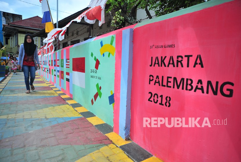 Warga melintasi salah satu bagian kampung yang telah dihiasi dengan warna warni logo Asian Games di Kampung Cempaka Bukit Kecil Palembang,sumsel, Ahad (24/6).