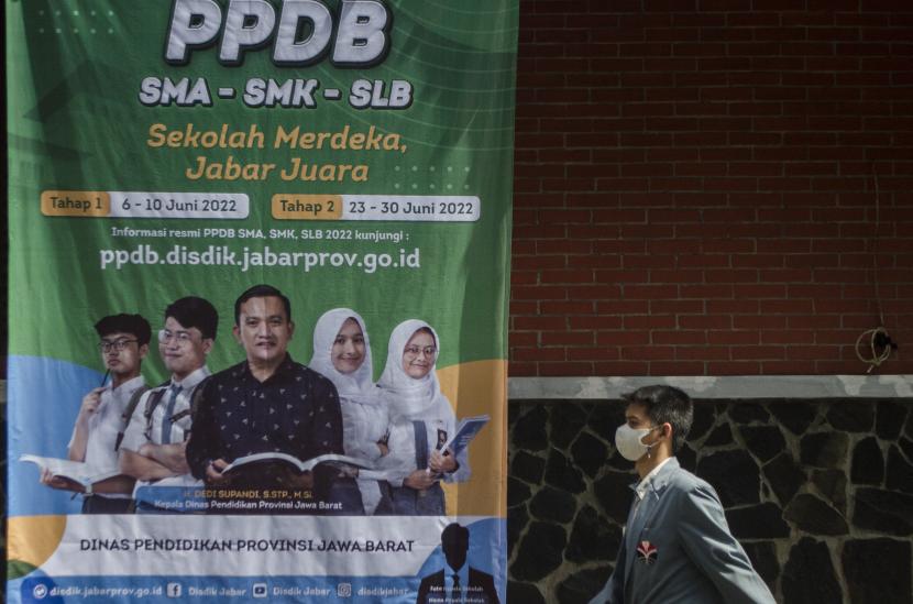 Warga melintasi spanduk informasi tahapan Penerimaan Peserta Didik Baru (PPDB) Jawa Barat 2022 di SMKN 2 Bandung, Jawa Barat, Selasa (17/5/2022). Dinas Pendidikan Jabar mengatakan PPDB akan tetap mempertahankan jalur hafiz Quran.