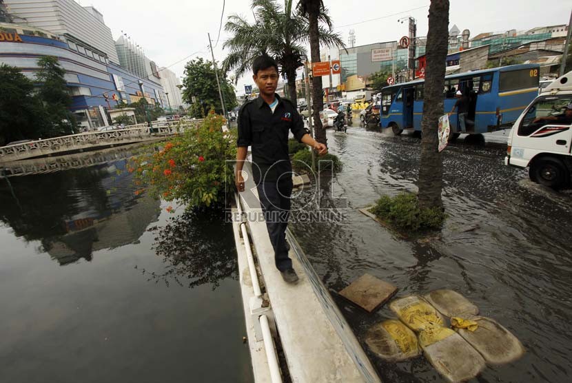  Warga melintasi tanggul kali untuk menghindari jalan yang tergenang air di kawasan Gunung Sahari, Mangga Dua, Jakarta Utara, Jumat (14/12).  (Republika/Adhi Wicaksono)