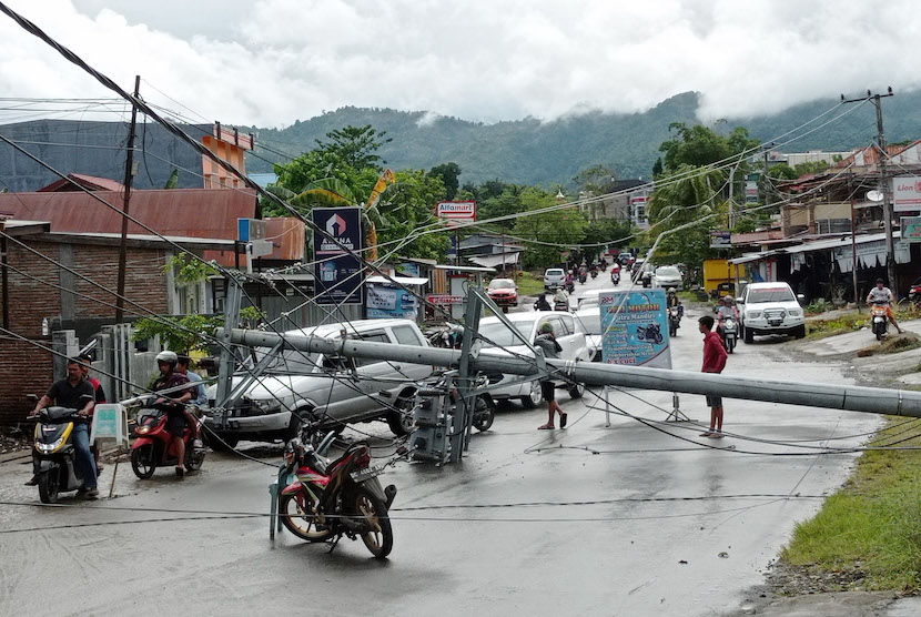 Warga melintasi tiang listrik yang melintang di jalan raya pascagempa bumi, di Mamuju, Sulawesi Barat, Jumat (15/1/2021).