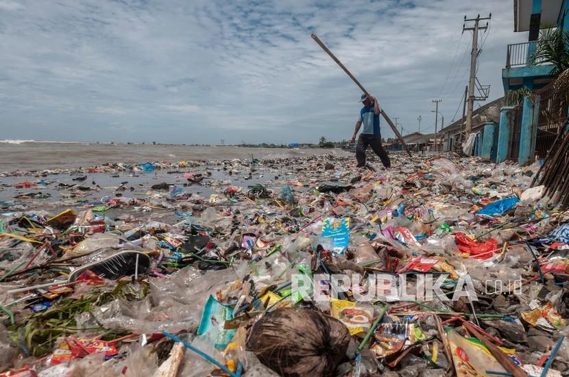 Warga melintasi tumpukan sampah yang terbawa ombak di Teluk Labuan, Pandeglang, Banten, Senin (7/2/2022). Sampah limbah rumah tangga tersebut terbawa oleh gelombang tinggi yang terjadi sejak beberapa hari terakhir di daerah itu. 