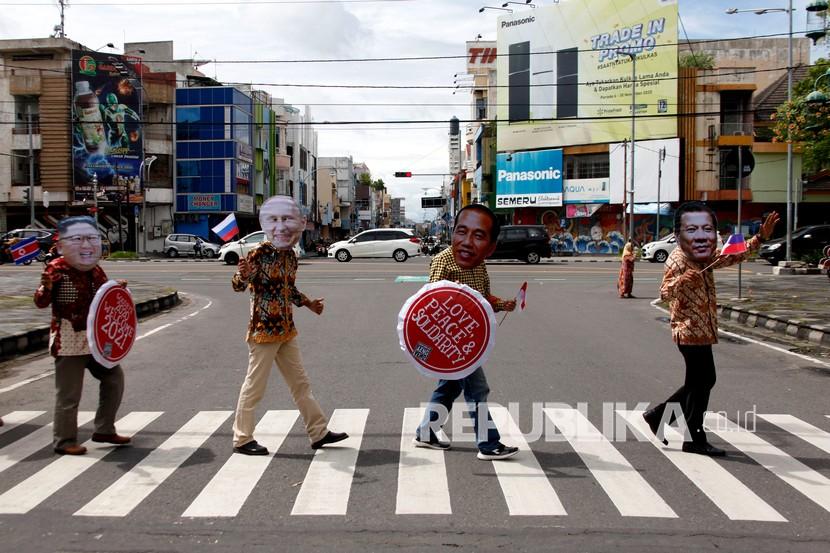 Warga memakai topeng sejumlah pemimpin dunia sambil membawa poster ucapan sambut tahun baru 2021 di kawasan Ngarsopuro, Solo, Jawa Tengah, Kamis (31/12/2020). Mereka berharap tahun baru akan membawa cinta, kedamaian dan solidaritas untuk dunia. 