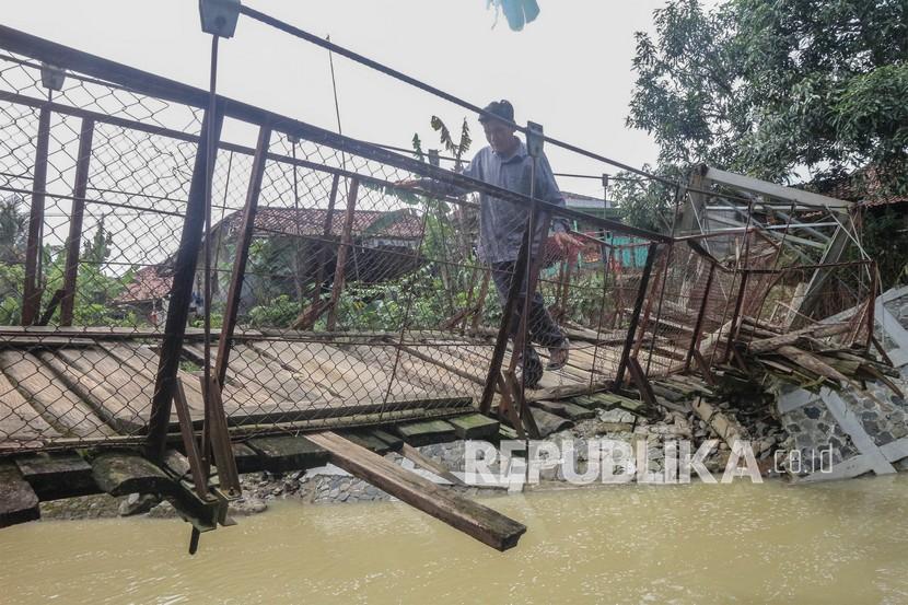Warga memaksakan diri melintasi jembatan rusak di Desa Sukarasa, Tanjung Sari, Kabupaten Bogor, Jawa Barat. Pemkab Bogor mencatat baru 30 desa yang memenuhi syarat pencairan dana samisade.