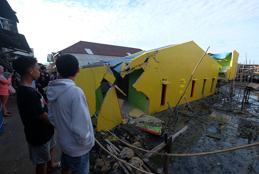 Warga memandang rumah yang rusak akibat gempa. Ilustrasi
