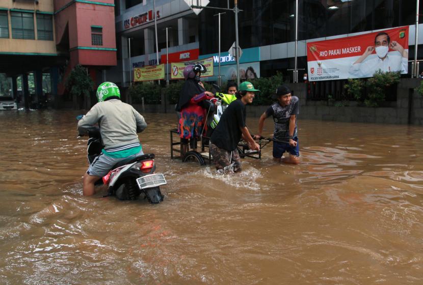Warga memanfaatkan ojek gerobak untuk melewati banjir di kawasan Pasar Raya Cipulir, Jakarta Selatan, Sabtu (20/2/2021).Banjir yang disebabkan luapan Kali Pesanggrahan akibat hujan di wilayah Jabodetabek pada Jumat (19/2) malam itu menyebabkan aktivitas jual beli terganggu.