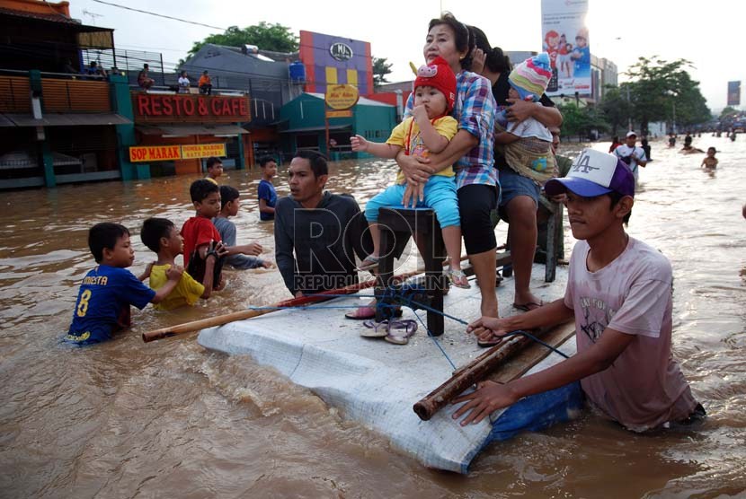   Warga memanfaatkan papan kayu untuk melintasi genangan air banjir yang merendam Jalan KH Abdullah Syafe'i, Kp melayu Besar, Jakarta, Jumat (18/1).  (Republika/Prayogi)