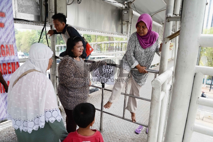 Warga memanjat portal larangan melintas Jembatan Penyebrangan Orang (JPO) sisi barat yang menghubungkan Polda Metro Jaya-Senayan, di Jalan Sudirman, Jakarta.   (Republika/Yasin Habibi)