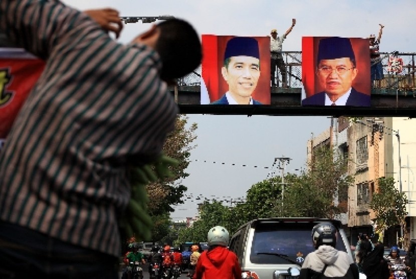 Warga memasang foto Joko Widodo dan Jusuf Kalla di salah satu jembatan penyeberangan di Solo, Kamis (23/10).