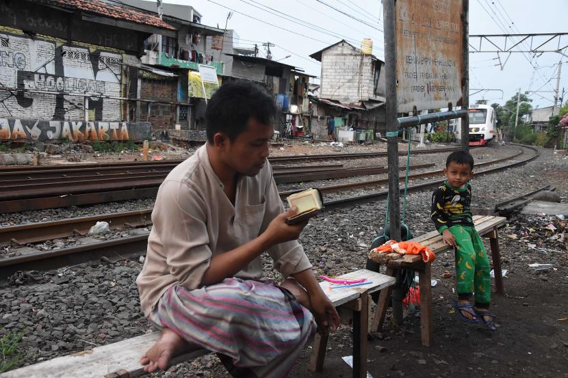 Warga membaca Alquran di bantaran rel saat masa pandemi COVID-19 di Menteng Tenggulun, Jakarta.