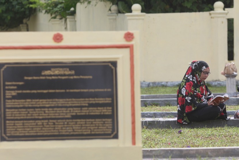 Warga membaca surah Yasin di kuburan massal korban tsunami saat peringatan 12 tahun tsunami di Desa Suak Indrapuri, Kecamatan Johan Pahlawan, Aceh Barat, Aceh, Senin (26/12). 