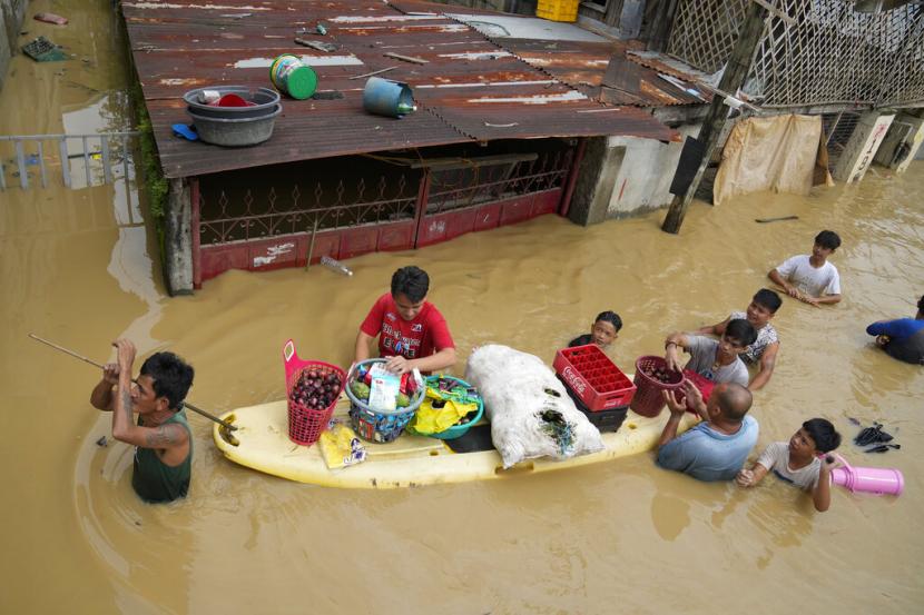 Warga membagikan sembako dan makanan lain di sepanjang jalan yang tergenang banjir akibat Topan Noru di kota San Miguel, provinsi Bulacan, Filipina, Senin, 26 September 2022.