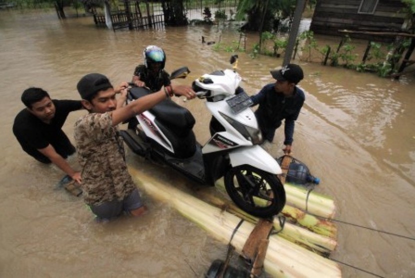 Warga membantu mengevakuasi sepeda motor guna melewati banjir di Desa Cot Girek Kandang, Muara Dua, Lhokseumawe, Aceh, Jumat (1/12). Banjir yang disebabkan tingginya intensitas hujan mengguyur provinsi Aceh sejak sepekan mengakibatkan sejumlah kabupaten/kota barat dan timur Aceh mulai teredam banjir. 