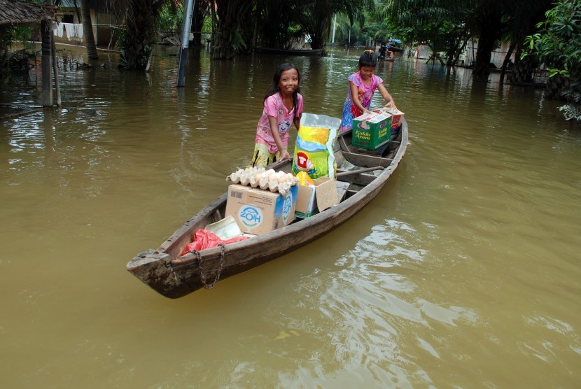 Warga membawa bantuan logistik menggunakan perahu ketika melintas di permukiman yang terendam banjir luapan Sungai Kampar di Desa Buluhcina, Kabupaten Kampar, Riau, Senin (15/2).