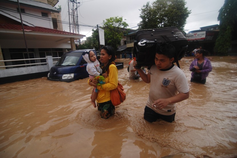  Warga membawa barang miliknya melintasi banjir ketika akan mengungsi ke tempat yang lebih aman di Wenang, Manado, Sulawesi Utara, Rabu (15/1).  (Antara/Fiqman Sunandar)