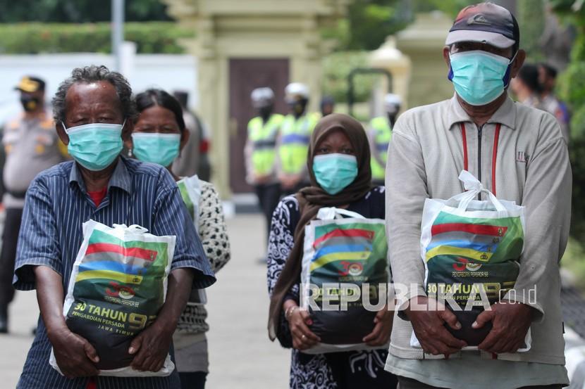Warga terdampak pandemi Covid-19 membawa paket sembako yang mereka terima di Tugu Pahlawan, Surabaya, Jawa Timur, Senin (7/3/2022). Pemerintah menyebut kondisi pandemi membaik dan tengah disiapkan prokes praendemi. 