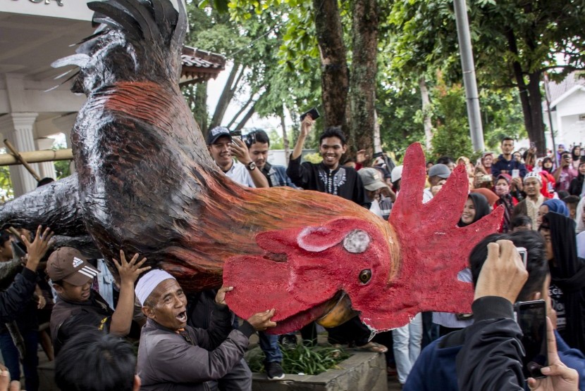 Warga membawa patung ayam yang merupakan simbol pemerintahan Cianjur saat aksi unjuk rasa terkait tertangkapnya bupati Cianjur di alun-alun, Kabupaten Cianjur, Jawa Barat, Jumat (14/12/2018).