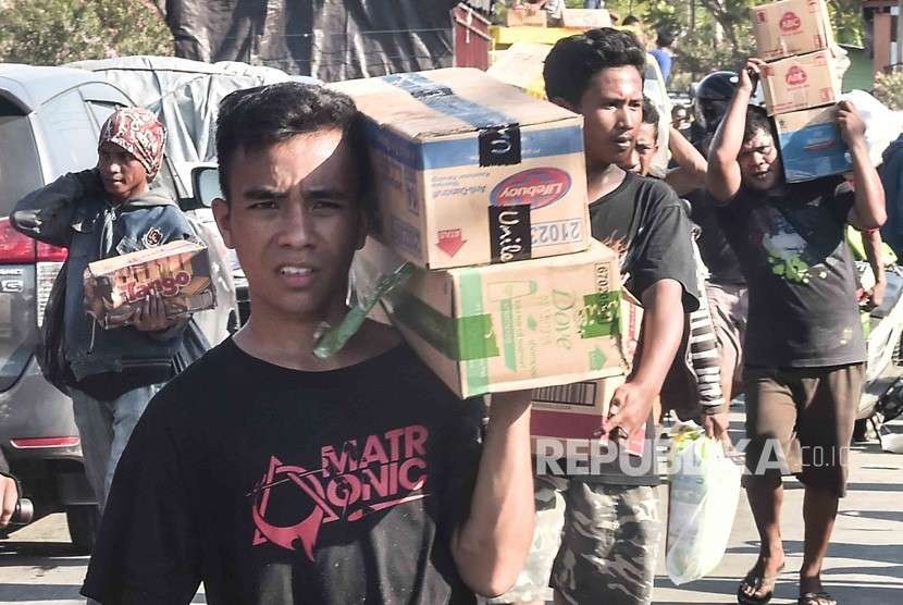 Warga membawa sejumlah barang dari gudang Alfa Midi di Mamboro, Palu Utara, Sulawesi Tengah, Senin (1/10).