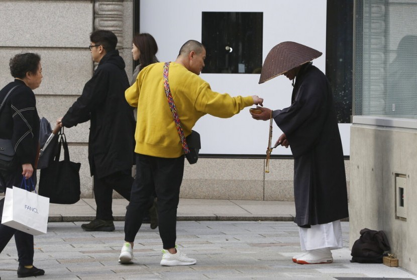 Warga memberi sedekah kepada biksu Budha di pusat perbelanjaan Ginza di Tokyo, Jepang, Rabu (13/11). Bank sentral Jepang menyatakan penggunaan uang kartal di Jepang masih tinggi untuk keperluan sehari-hari.