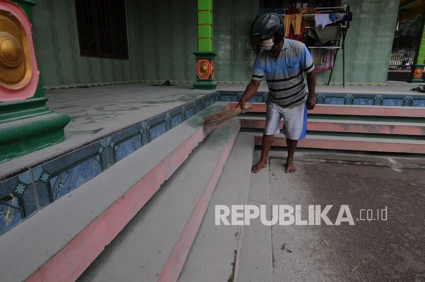 Warga membersihkan abu vulkanik Gunung Merapi yang menutupi halaman rumahnya. 