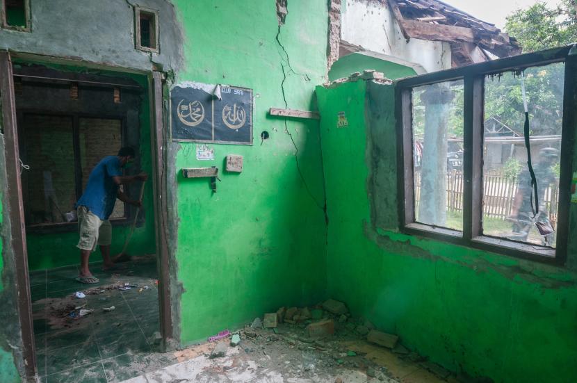 Warga membersihkan bangunan rumahnya yang rusak akibat gempa bumi di Sumur, Pandeglang, Banten.