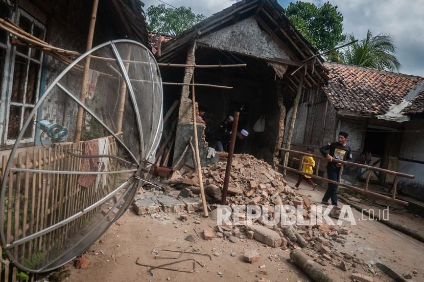 Warga membersihkan bangunan rumahnya yang rusak di Sumur, Pandeglang, Banten.