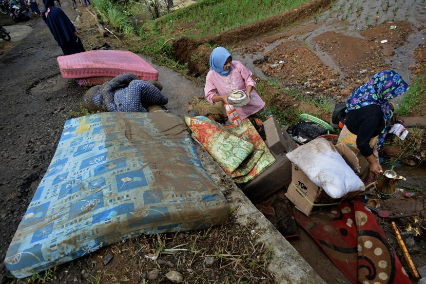 Warga membersihkan barang-barang yang terkena banjir di Desa Dangiang, Banjarwangi, Kabupaten Garut, Jawa Barat, Selasa (9/2/2021). Banjir dari luapan Sungan Cidangiang merendam sebanyak 48 rumah dan mengakibatkan 171 jiwa terdampak banjir.