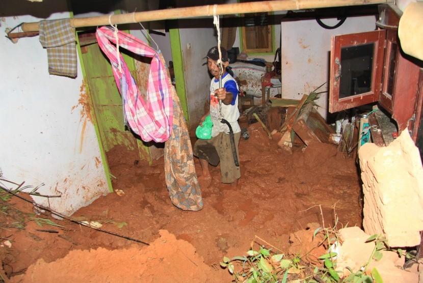 Warga membersihkan meterial tanah longsor yang menghantam rumahnya di Desa Kalijati, Kabupaten Pangandaran, Jawa Barat, Sabtu (7/10). Akibat hujan deras yang mengguyur Kabupaten Pangandaran mengakibatkan empat orang tewas tertimbun tanah longsor. 