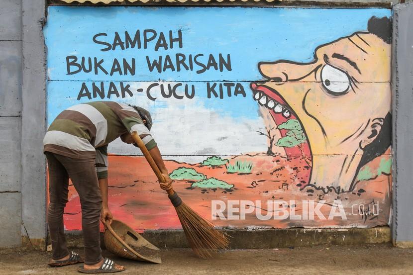 Warga membersihkan sampah di depan mural larangan buang sampah sembarangan di Serua, Depok, Jawa Barat, Jumat (4/3/2022). Mural dengan tema larangan buang sampah sembarangan tersebut diinisiasi oleh Komunitas Mural Art Serua sebagai media memberikan peringatan dan himbauan kepada warga untuk tidak membuang sampah sembarangan di kawasan itu. Naskah Khutbah Jumat: Menjaga Kebersihan Diri dan Lingkungan