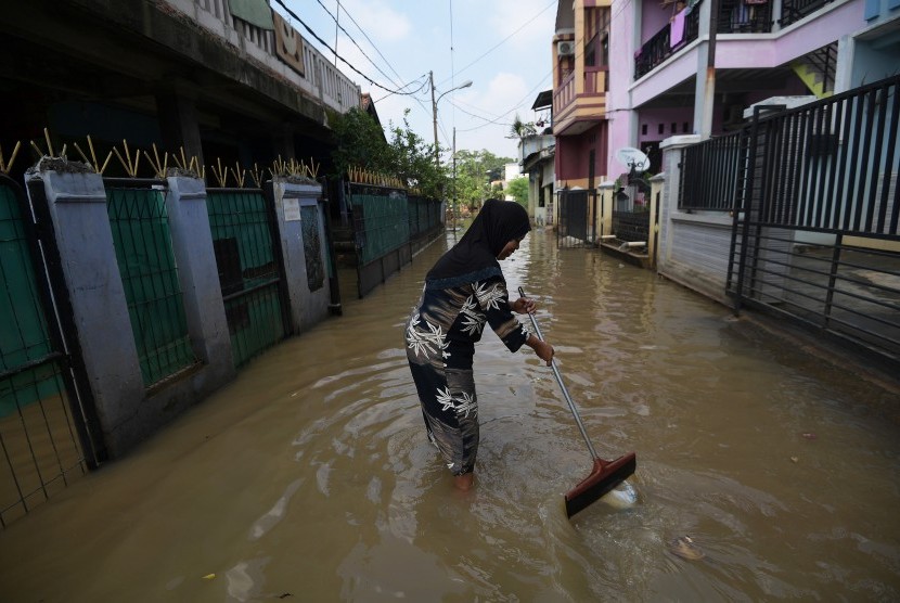 Warga membersihkan sampah saat banjir menggenangi kawasan Cipinang Melayu, Kecamatan Makasar, Jakarta Timur, Minggu (26/2). 