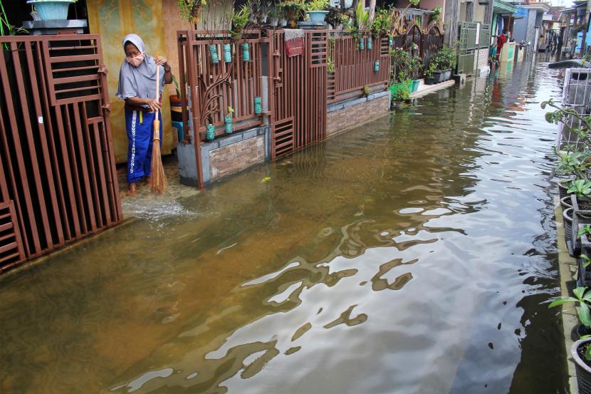 Warga membersihkan sampah saat banjir rob di Dusun Bandaran, Kecamatan Paragan, Bangkalan, Jawa Timur, Jumat (20/5/2022). Pasang air laut yang terjadi selama dua hari di kawasan pesisir tersebut mengakibatkan rumah warga terendam banjir dengan variasi ketinggian antara 30-50 cm.