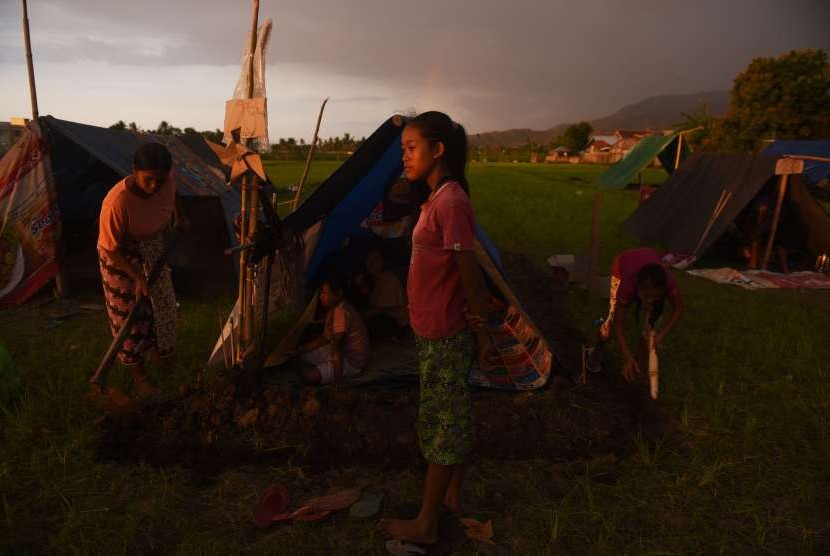 Warga membuat parit di sekililing tenda darurat yang mereka bangun di pematang sawah di Tanjung, Lombok Utara, Jawa Timur, Kamis (9/8).