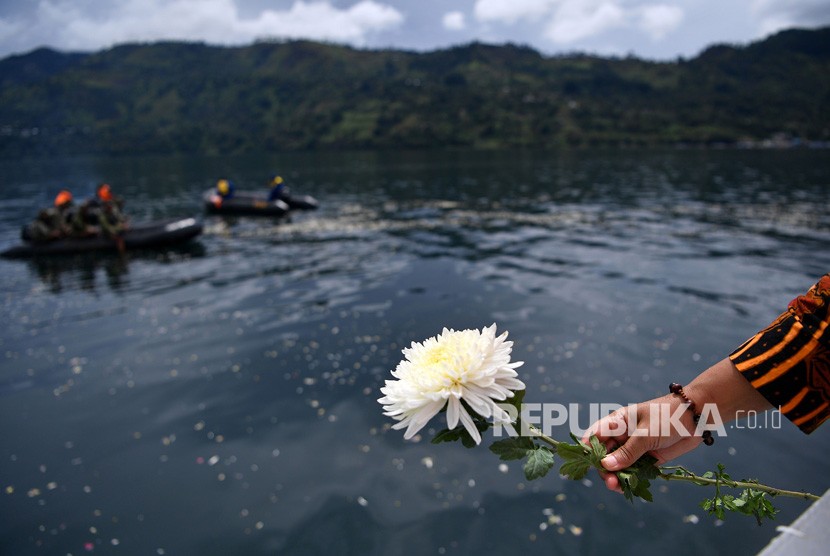 Warga memegang bersiap melemparkan bunga dalam prosesi tabur bunga untuk korban tenggelamnya KM Sinar Bangun di kawasan titik tenggelamnya kapal di Danau Toba, Sumatera Utara, Senin (2/7).