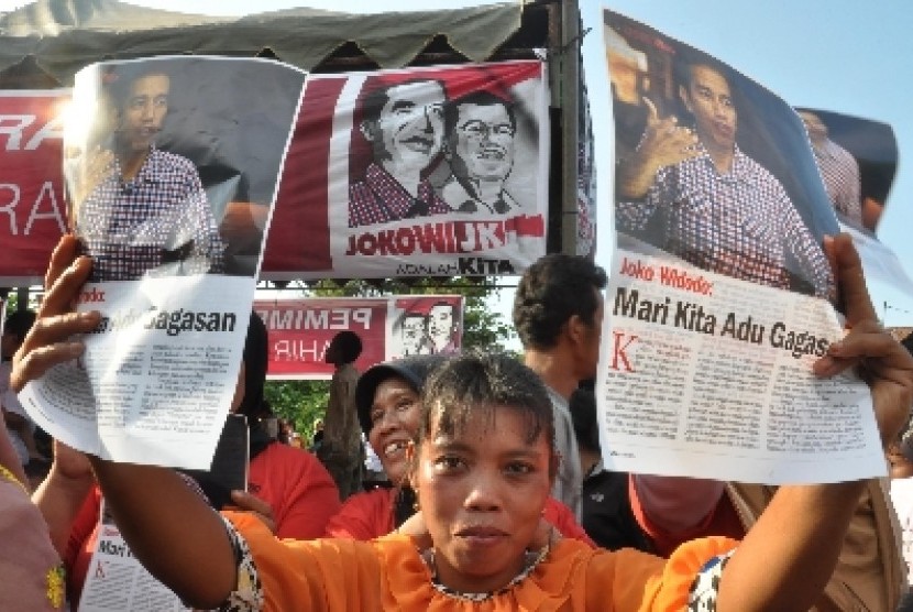 Warga memegang poster bergambar Calon Presiden Joko Widodo