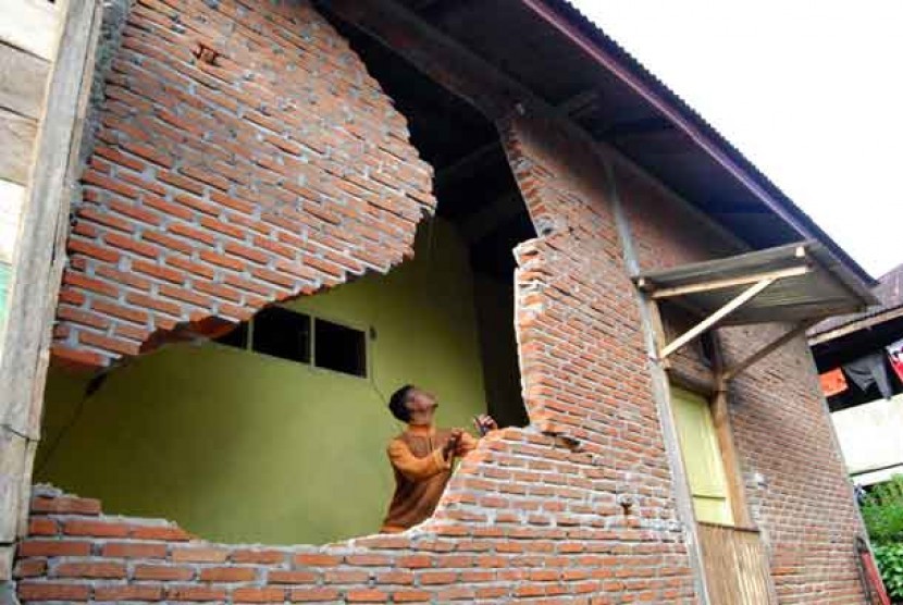 Warga memeriksa dinding rumahnya yang roboh akibat gempa di Desa Neubok Badeuk, Kecamatan Tangse, Kabupaten Pidie, Aceh, Rabu (23/10).  