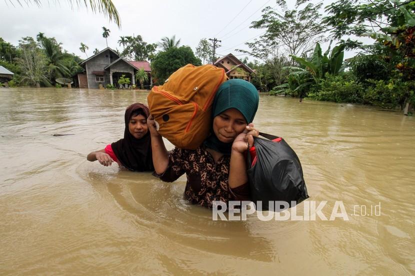 Warga memikul harta bendanya untuk keluar dari kepungan banjir di Desa Hagu, Kecamatan Matang Kuli, Aceh Utara, Aceh.
