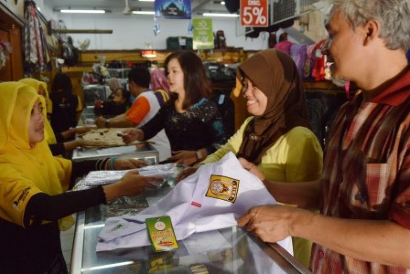 Warga memilih pakaian seragam sekolah untuk anak mereka di sebuah toko peralatan sekolah, Ahad (26/7)