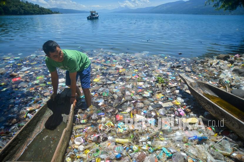 Warga memindahkan biduk di antara sampah di tepian Danau Singkarak, Nagari Sumpu, Kabupaten Tanah Datar, Sumatera Barat, Kamis (20/1/2022). Tepian danau wisata tersebut dipenuhi sampah plastik sejak sepekan terakhir yang menyulitkan nelayan mencari ikan.