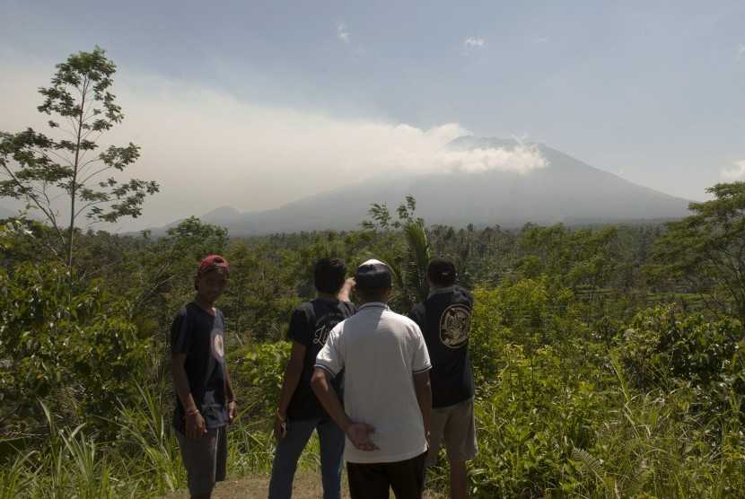 Warga memotret asap yang mulai mengepul dari kawah Gunung Agung dari Pos Pemantauan Desa Rendang, Karangasem, Bali, Selasa (19/9). 