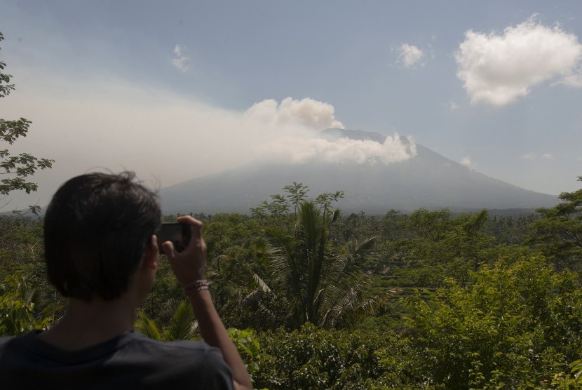 Warga memotret asap yang mulai mengepul dari kawah Gunung Agung dari Pos Pemantauan Desa Rendang, Karangasem, Bali, Selasa (19/9). 