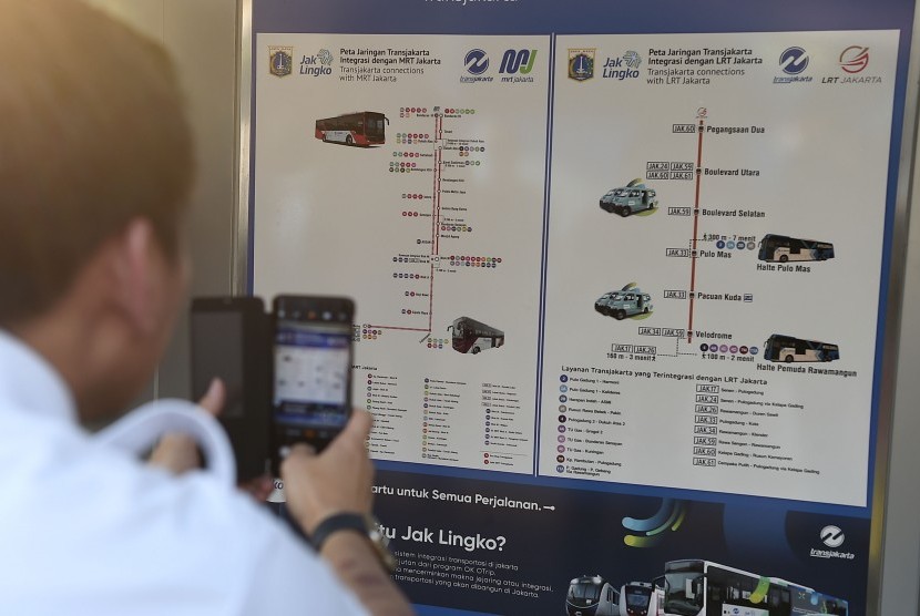 Warga memotret media informasi moda transportasi publik yang baru diresmikan Gubernur DKI Jakarta Anies Baswedan di Halte Gelora Bung Karno, Jakarta, Selasa (13/8). Pemerintah Provinsi DKI Jakarta memasang media informasi yang mengintegrasikan seluruh moda transportasi publik di 28 halte pada tahap pertama dan seluruh halte yang ada se-Jakarta pada tahap-tahap selanjutnya.
