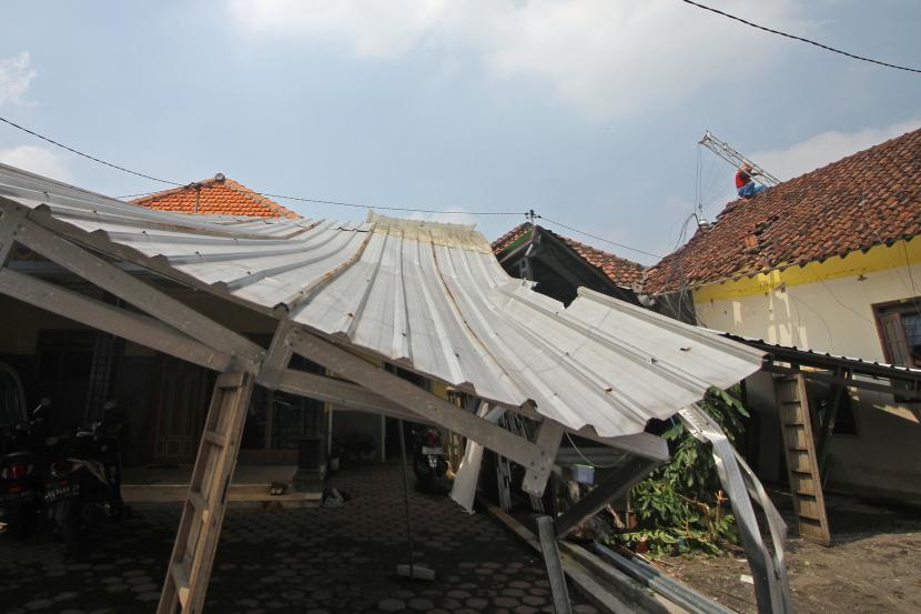 Warga memperbaiki atap rumah yang terdampak angin puting beliung. Atap rumah yang menggunakan asbes dapat picu kanker paru.