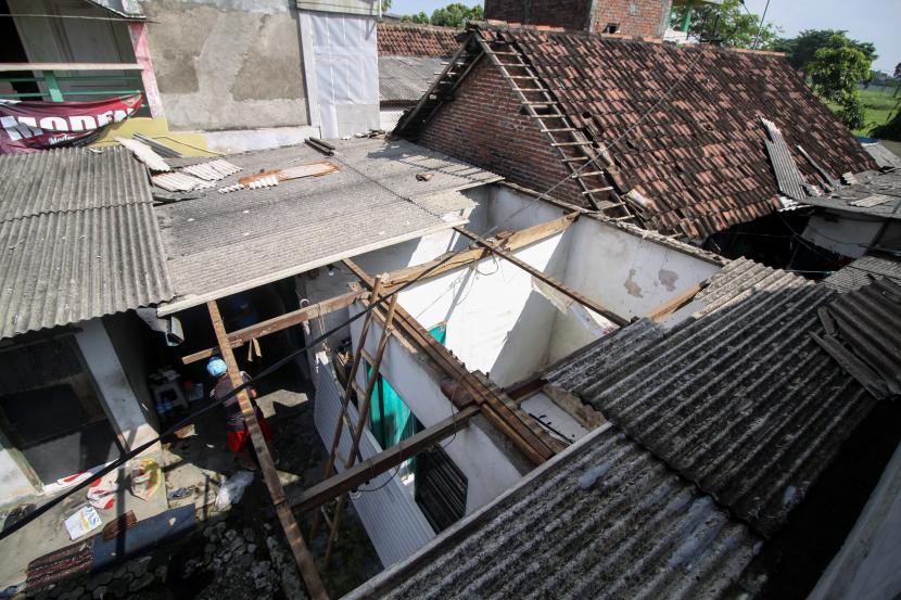 Warga memperbaiki rumahnya yang rusak setelah diterjang angin puting beliung. (Ilustrasi)