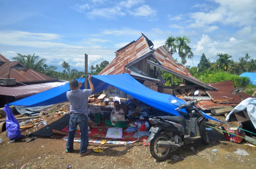 Warga memperbaiki tenda yang didirikan di depan rumahnya yang rusak akibat gempa di Nagari Malampah, Kecamatan Tigo Nagari, Kabupaten Pasaman, Sumatera Barat, Senin (7/3/2022). Data terakhir BNPB, sebanyak 1.736 rumah terverifikasi tingkat kerusakan akibat gempa magnitudo (M) 6,1 di Kabupaten Pasaman, dengan rincian 651 rumah rusak berat, 355 rusak sedang dan 730 rusak ringan. 