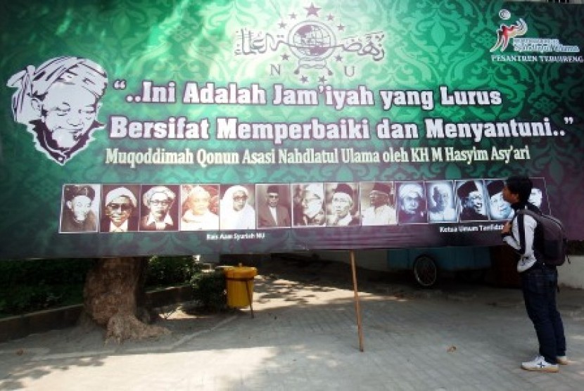 Warga memperhatikan foto sejumlah tokoh NU pada baliho Muktamar ke-33 Nahdlatul Ulama yang terpasang di Ponpes Tebuireng, Jombang, Jawa Timur, Ahad (26/7). 