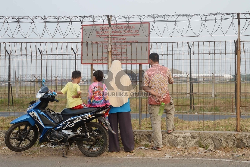 Warga memperhatikan pesawat komersial yang akan mendarat di landasan pacu Bandara Internasional Soekarno Hatta, Tangerang, Banten, Selasa (22/9).