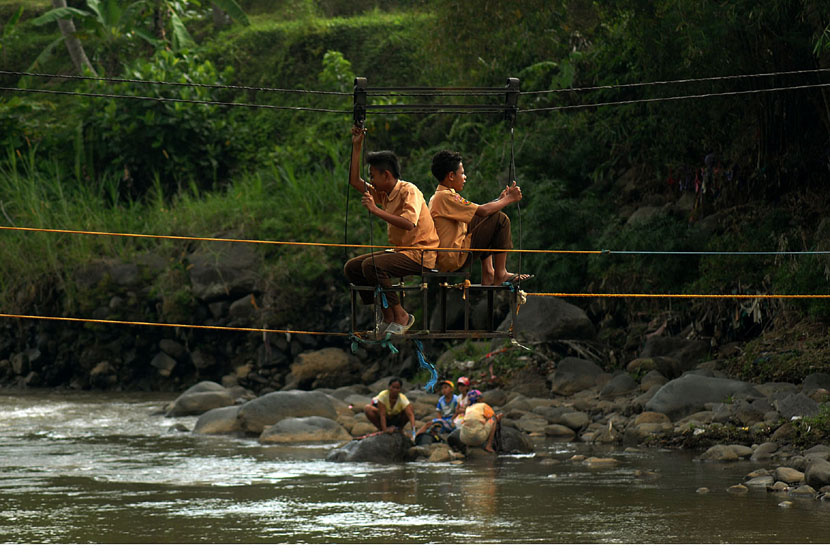  Dua pelajar menggunakan jembatan kerek untuk menyeberangi Sungai Ciwulan di Kampung Pamimpiran, Lewiliang, Tasikmalaya, Jawa Barat, Jumat (7/11). (Antara/Adeng Bustomi)