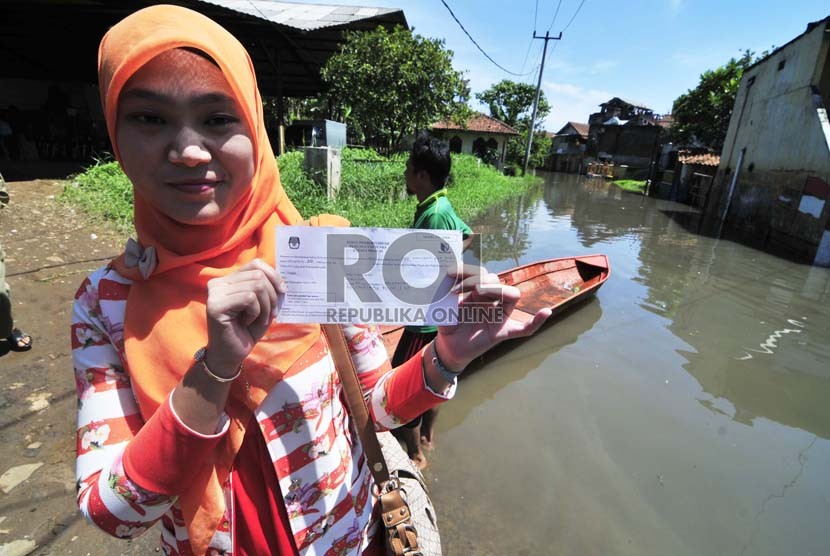 Warga memperlihatkan surat pemberitahuan pemungutan suara saat mengikuti pemilihan Kepala Daerah periode 2015-2020 di Cieunteung, Kabupaten Bandung, Rabu(9/12). (Republika/Septianjar Muharam)