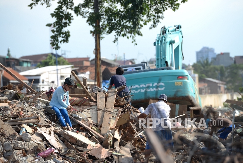 Warga memungut besi sisa bangunan usai gusuran di Bukit Duri, Jakarta, Kamis (29/9). 